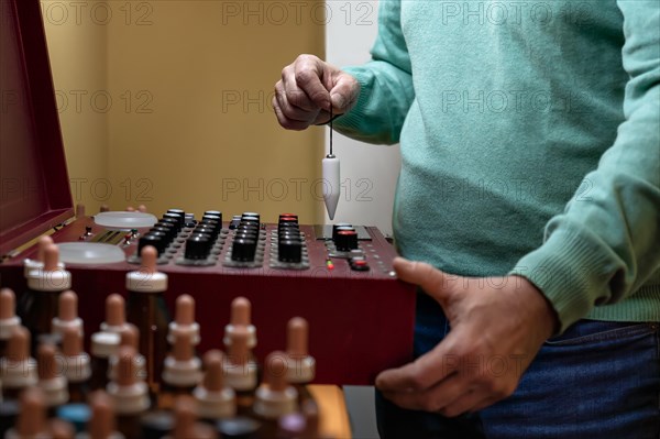 Adult man performing analysis with a radionic machine