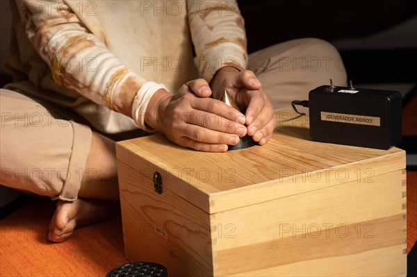 Hands of a patient resting on a machine that transmits torsion field energy in order to promote health