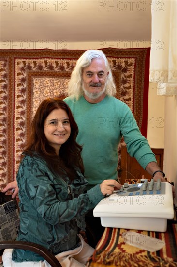 Man and woman looking and smiling at camera in an office performing a diagnosis with a radionic machine