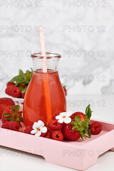 Red strawberry fruit lemonade in jar surrounded by berries