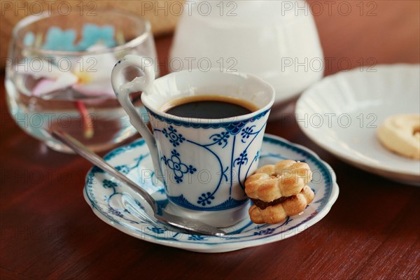 A shot of an espresso in an elegant ceramic demitasse with a biscuit at a cafe