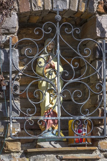 Figure of the Virgin Mary behind a barred niche