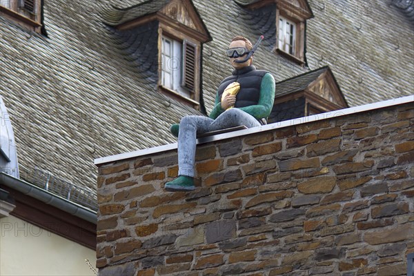 Male figure with diving goggles and snorkel sitting on a wall