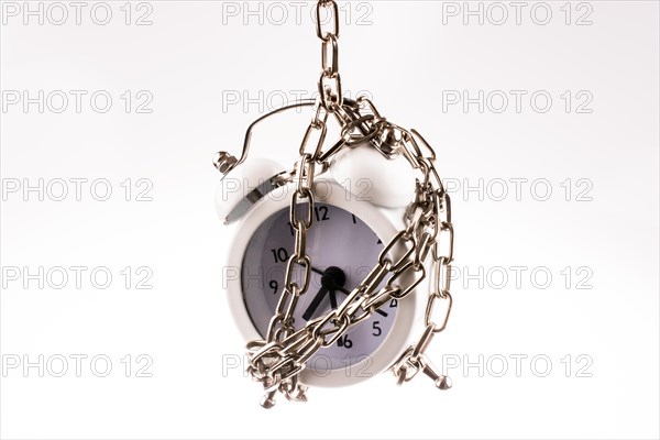 White color alarm clock in chain on a white background