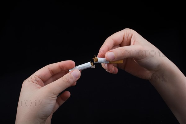 Hand is breaking a cigarette on a black background