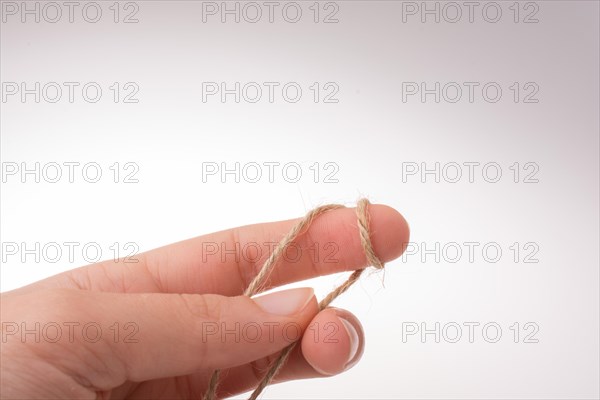 Hand holding linen thread on a white background