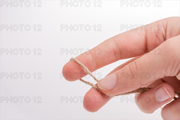 Hand holding linen thread on a white background