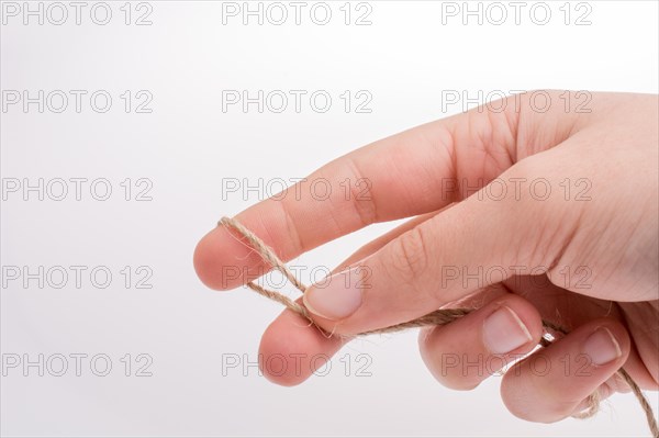 Hand holding linen thread on a white background