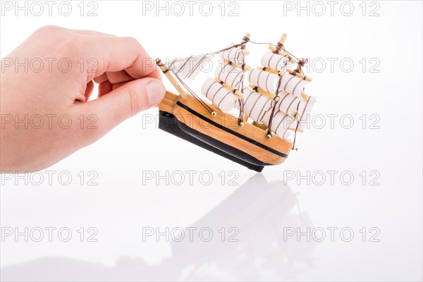 Hand in touch with a little model sailboat on a white background