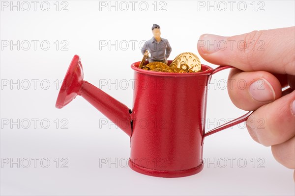 Figurine man standing in a watering can full of fake gold coins