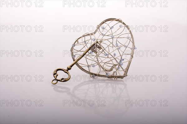 Key and a heart shaped metal cage on white