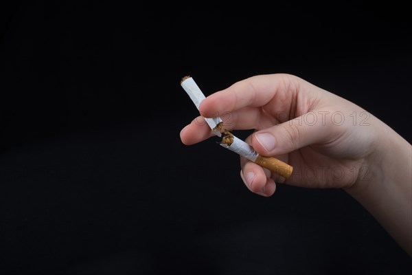 Hand is breaking a cigarette on a black background