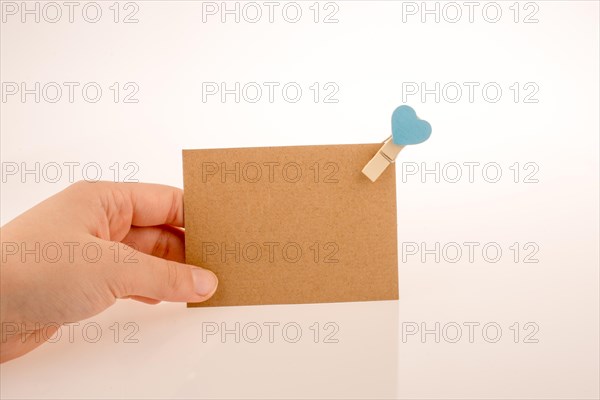 Hand holding a paper placed in a clothespin withe heart on a white background