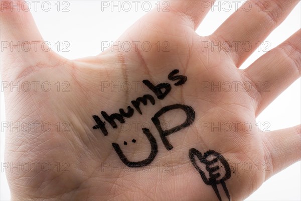 Thumbs up written on hand palm on a white background