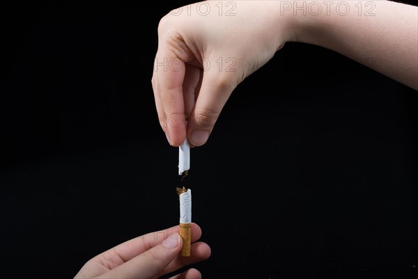 Hand is breaking a cigarette on a black background