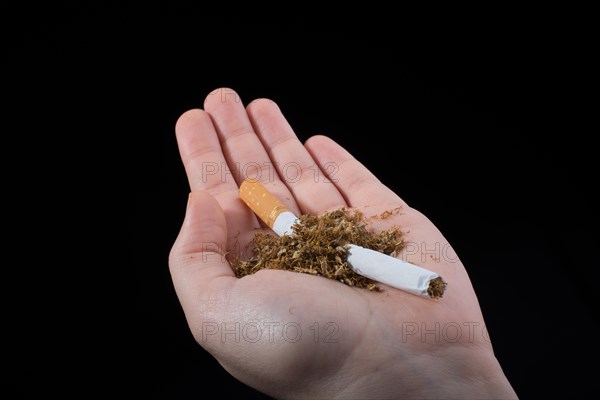 Hand is breaking a cigarette on a black background