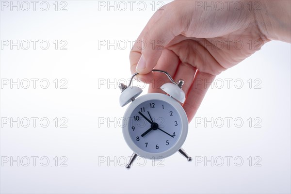 Alarm clock in hand on a white background