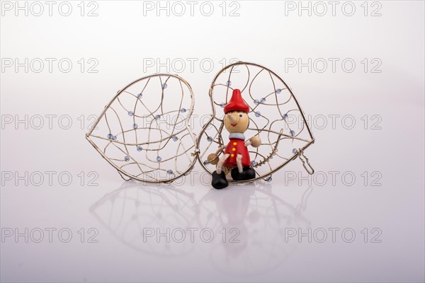 Wooden Pinocchio doll sitting on a heart shaped cage