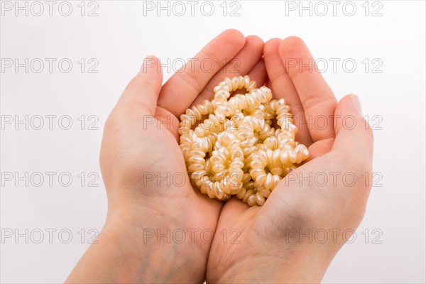 Hand holding pearl necklace on white background