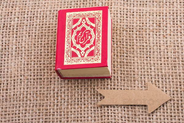 Paper arrow and Islamic Holy Book Quran in mini size