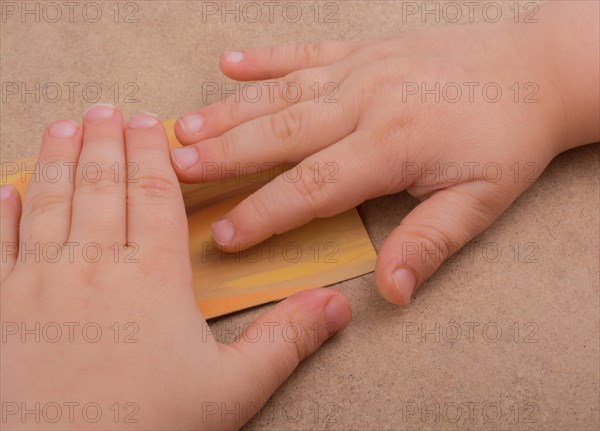 Hand holding painted note paper on brown background