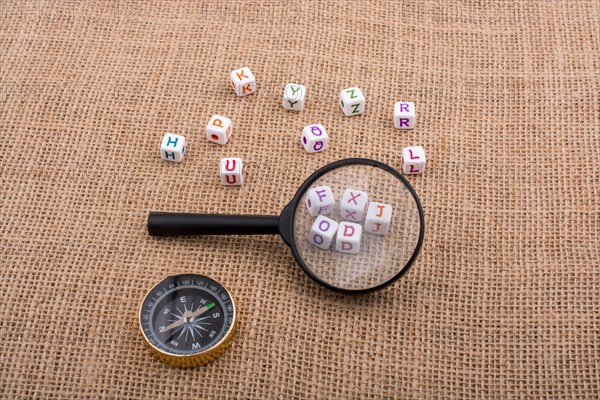 Compass and colorful letter cubes behind a magnifying glass