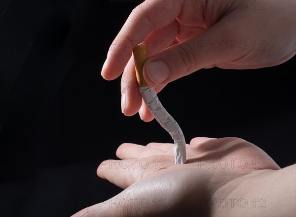 Hand is breaking a cigarette on a black background