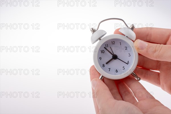 Alarm clock in hand on a white background