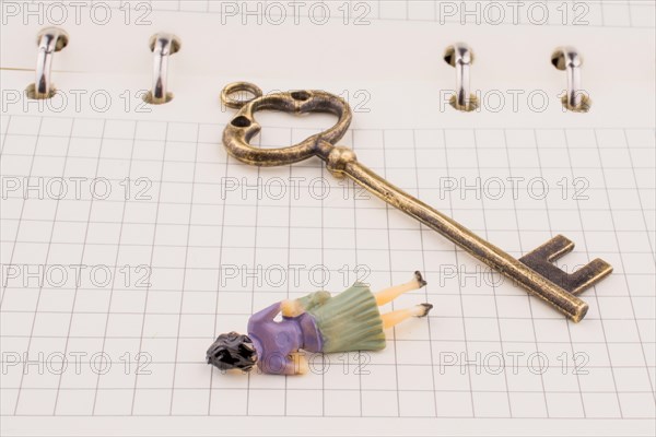 Human figure near a key on a white spiral notebook