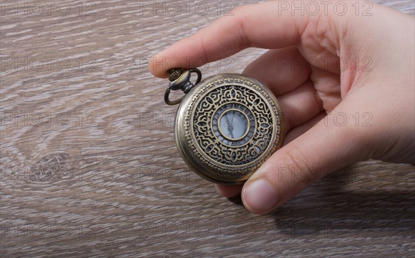 Retro style pocket watch in hand on black background