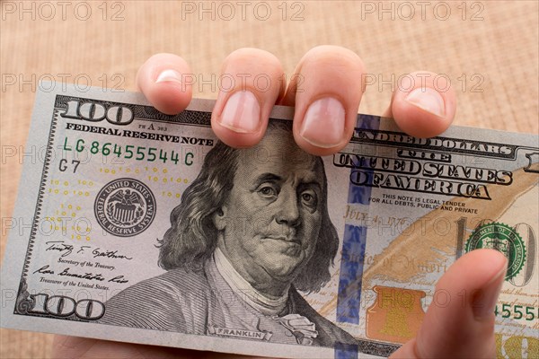 Hand holding banknote bundle of US dollar on a linen canvas background