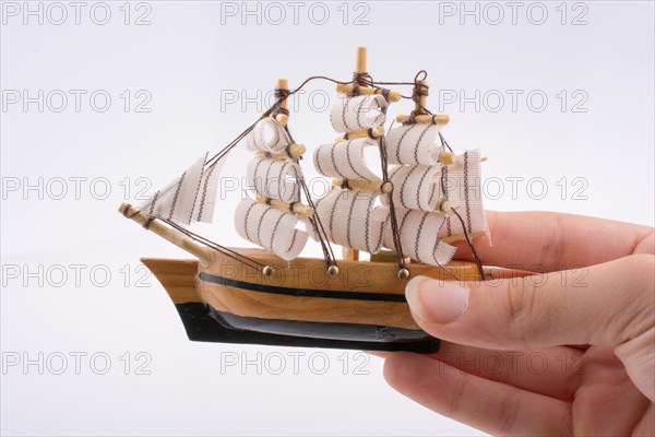 Little colorful model boat in hand on white background