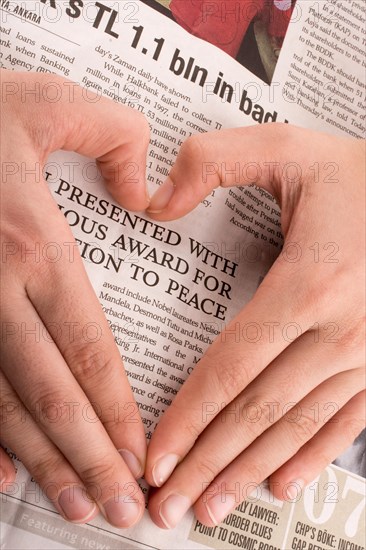 Hand making a heart shape on a newspaper