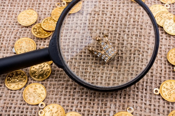 Crown under magnifying glass with fake gold coins