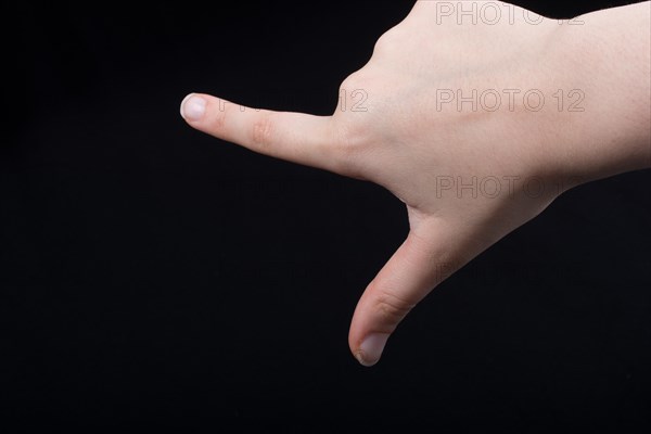 Hand gesture pointing fingers pistol-like handgun on black