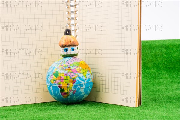 Hut on a Globe near a notebook on green grass