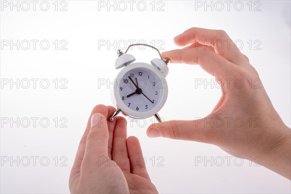 Alarm clock in hand on a white background