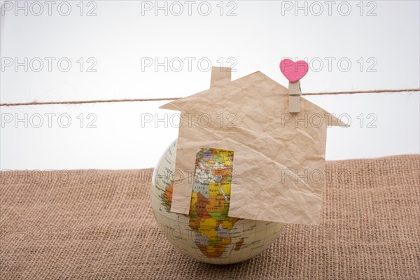 Little paper house attached to a string with a heart clip by a globe
