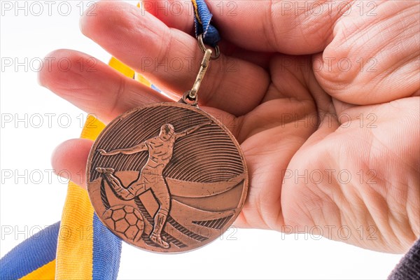 Hand holding a medal with blue and yellow ribbon