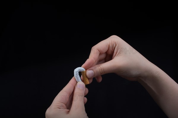 Hand is breaking a cigarette on a black background