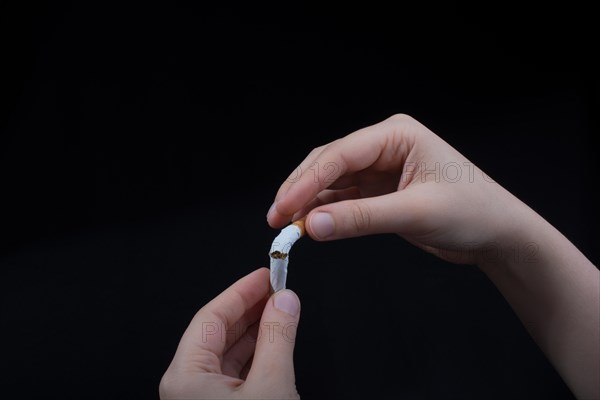 Hand is breaking a cigarette on a black background