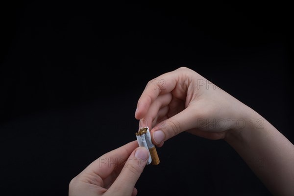 Hand is breaking a cigarette on a black background