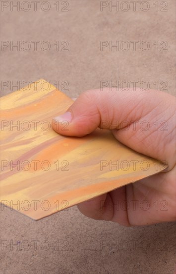 Hand holding painted note paper on brown background