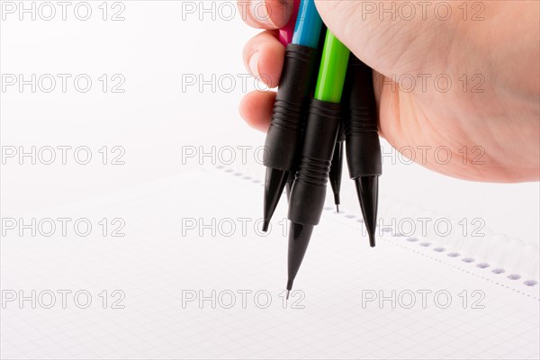 Mechanical pencils of various color in hand on white background