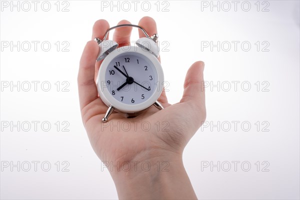 Alarm clock in hand on a white background