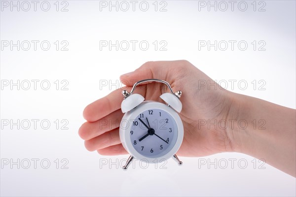 Alarm clock in hand on a white background