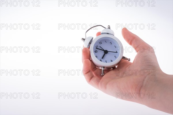 Alarm clock in hand on a white background