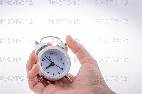 Alarm clock in hand on a white background