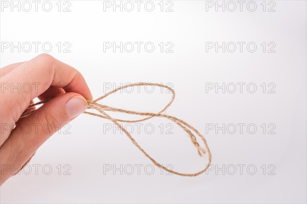 Hand holding linen thread on a white background