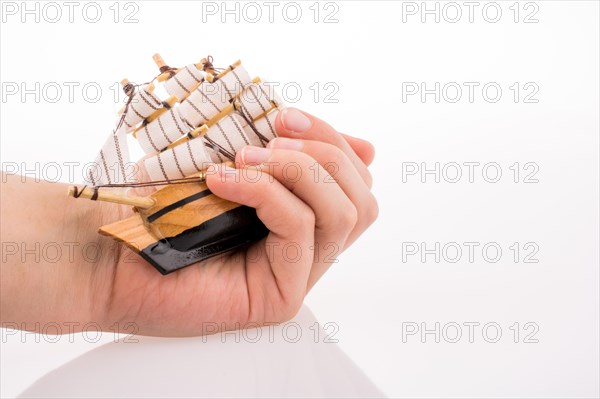Hand holding a Little model sailboat on a white background